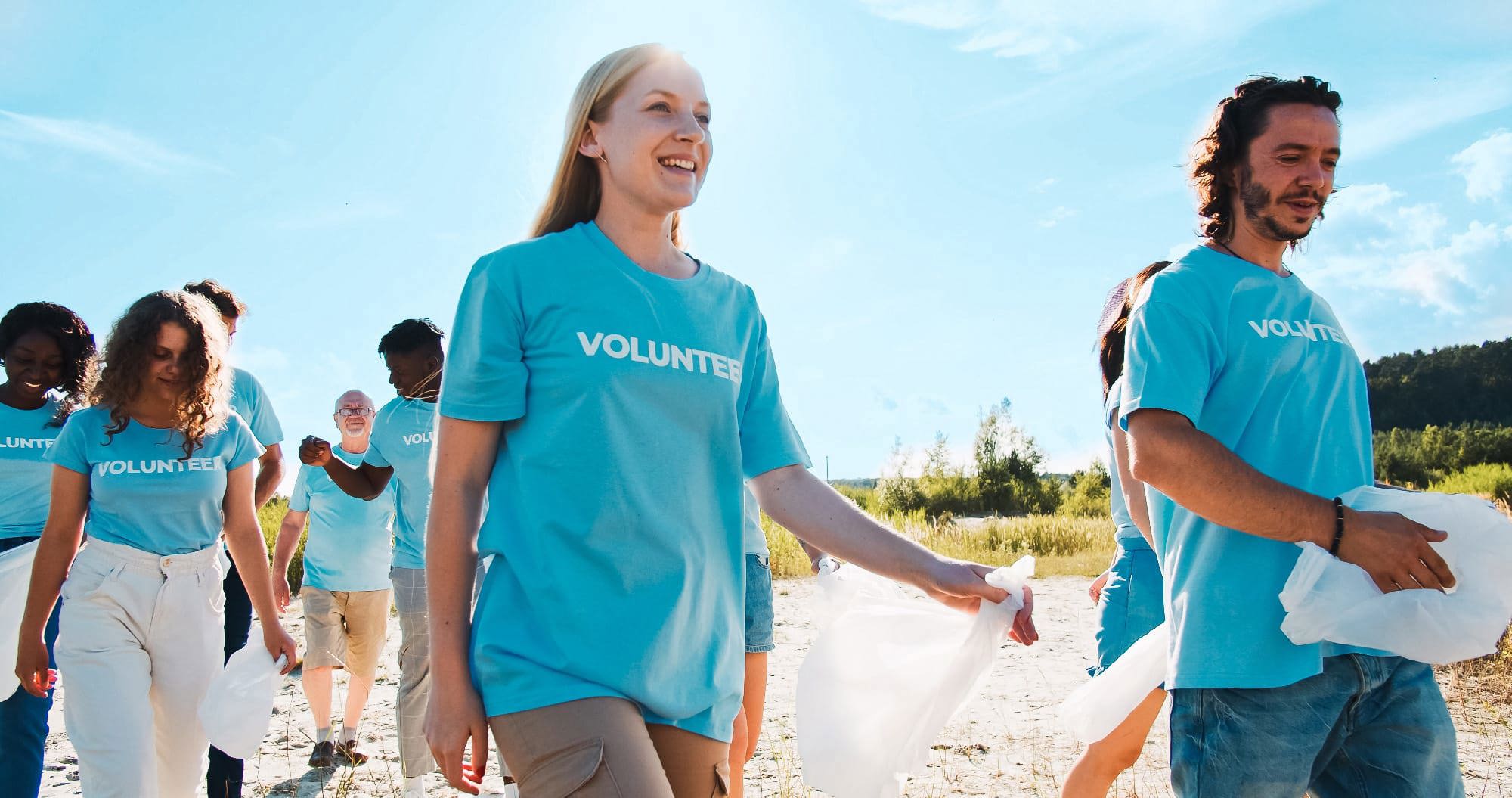 A group of volunteers in blue shirts cleaning up the environment.